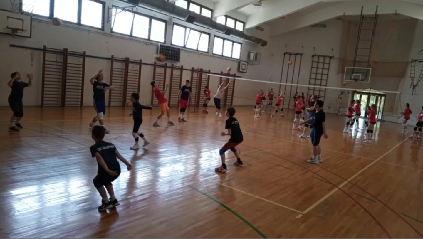 Djeca na treningu škole odbojke Mornara u školskoj sali, vježbe sa loptom uz mrežu